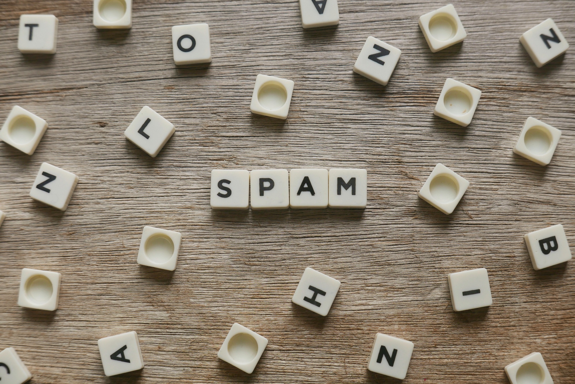 Spam word made of square letter word on wooden background.