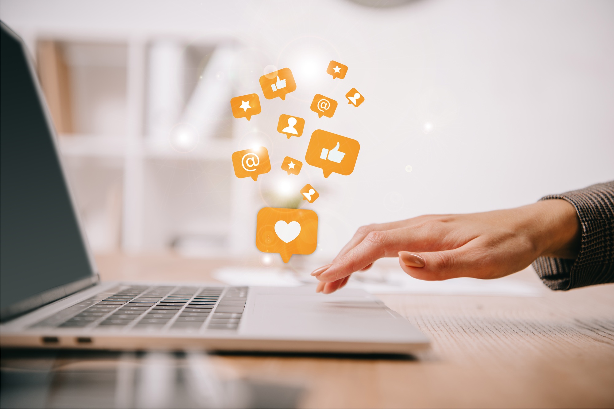 Hand tippt auf Laptop mit Social-Media-Symbolen